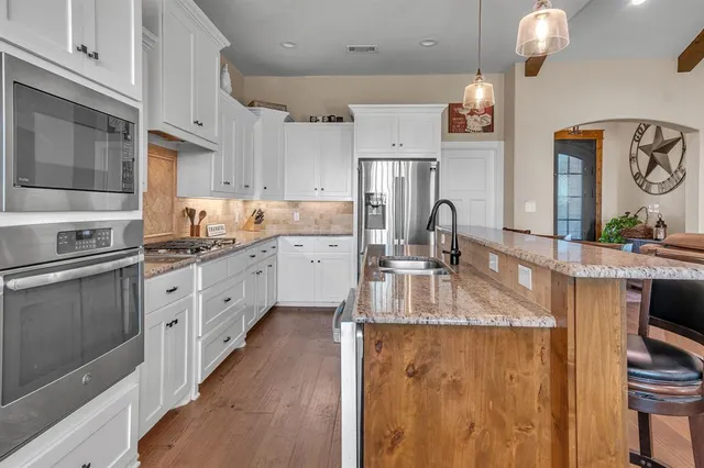 a kitchen with granite countertop a sink stove and refrigerator