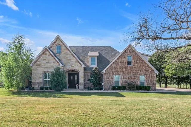 a front view of house with yard and trees in the background