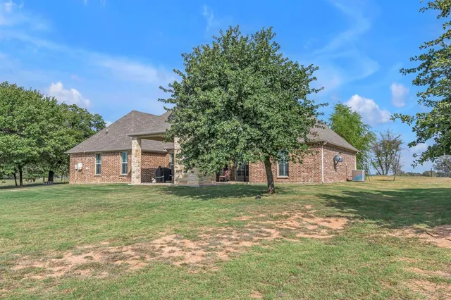 a front view of house with yard and trees in the background