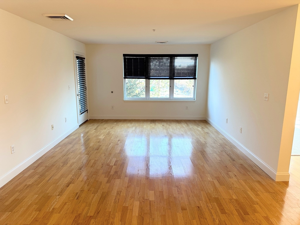 318 Rindge Avenue, Unit 216 Cambridge, MA 02140 - Photo 2 of 15 wooden floor in an empty room with a window