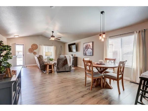a view of a dining room and livingroom with furniture wooden floor a rug a flat screen tv a painting and a chandelier