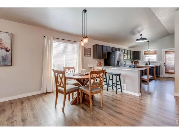 a dining room with furniture wooden floor and a kitchen view