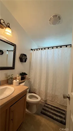 a bathroom with a sink a toilet a mirror and shower curtain