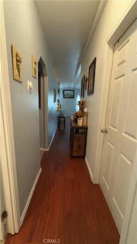 a view of a hallway to rooms and wooden floor