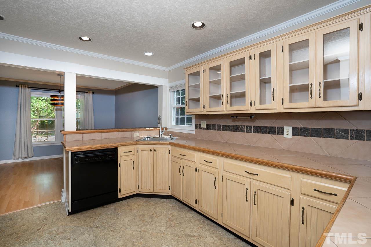 7405 Mine Valley Road Raleigh, NC 27615 - Photo 11 of 24 a large white kitchen with granite countertop a sink and dishwasher a stove with wooden floors