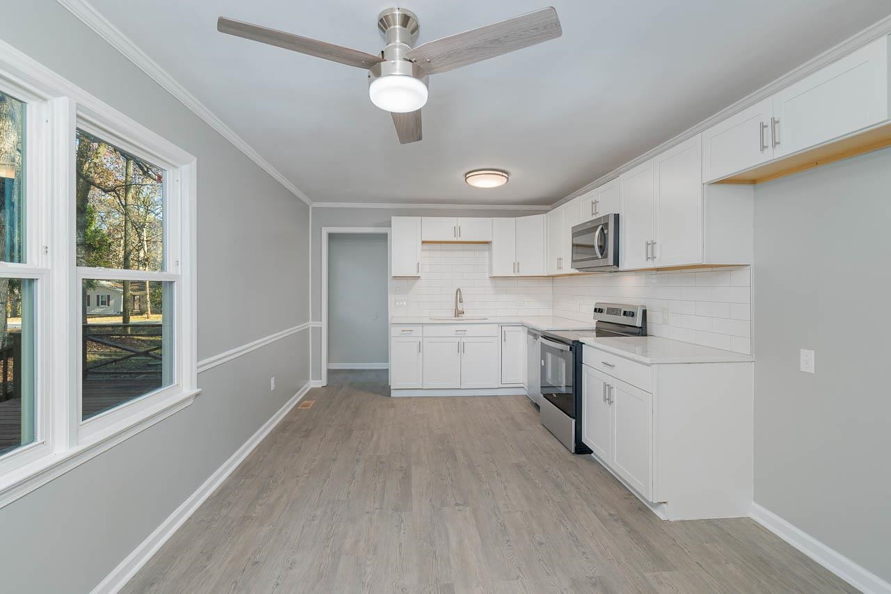 5917 Meadowlark Lane Raleigh, NC 27610 - Photo 10 of 24 a kitchen with a refrigerator a sink dishwasher a stove and white cabinets with wooden floor