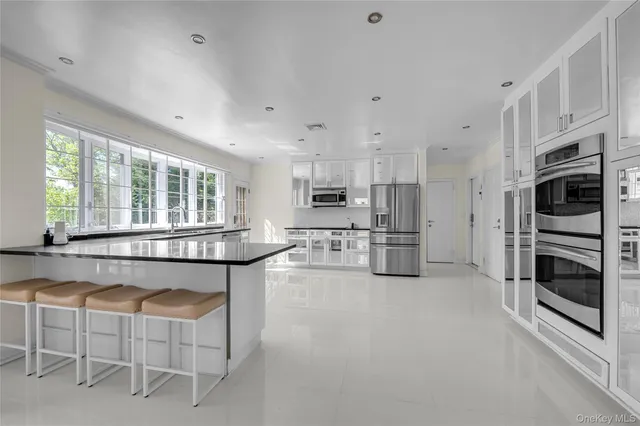 a kitchen with stainless steel appliances granite countertop a stove top oven a refrigerator a kitchen island white cabinets and a refrigerator