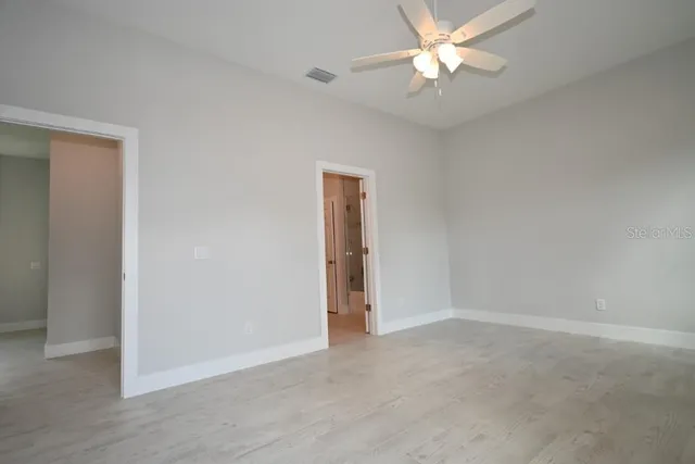 an empty room with closet and a chandelier fan