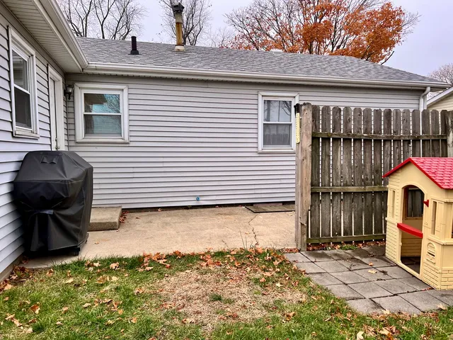 a backyard of a house with wooden fence and a toy car