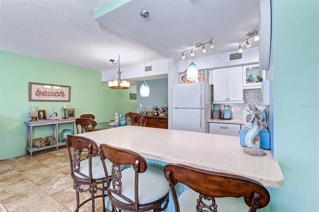17400 Gulf Boulevard, Unit H2 Redington Shores, FL 33708 - Photo 12 of 36 a kitchen with stainless steel appliances granite countertop a refrigerator a microwave a dining table and chairs with wooden floor