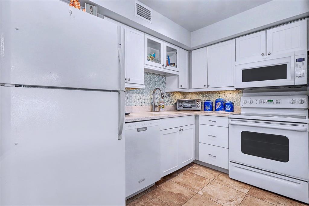 17400 Gulf Boulevard, Unit H2 Redington Shores, FL 33708 - Photo 13 of 36 a kitchen with stainless steel appliances white cabinets and white appliances