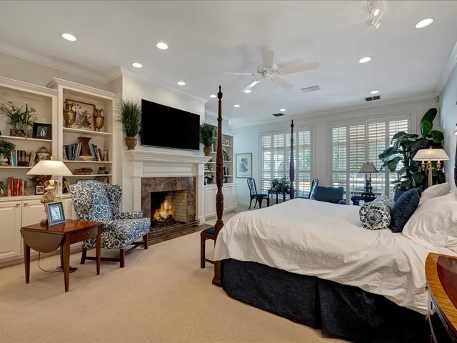 a large bedroom with a large bed a flat tv screen and a fireplace