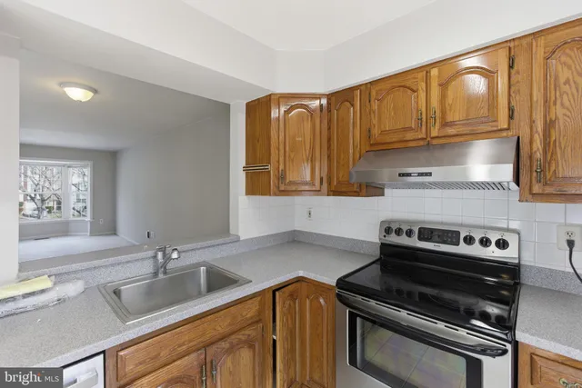 a kitchen with granite countertop a sink stove and cabinets