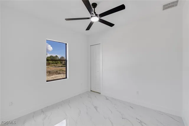 an empty room with a window and a fan