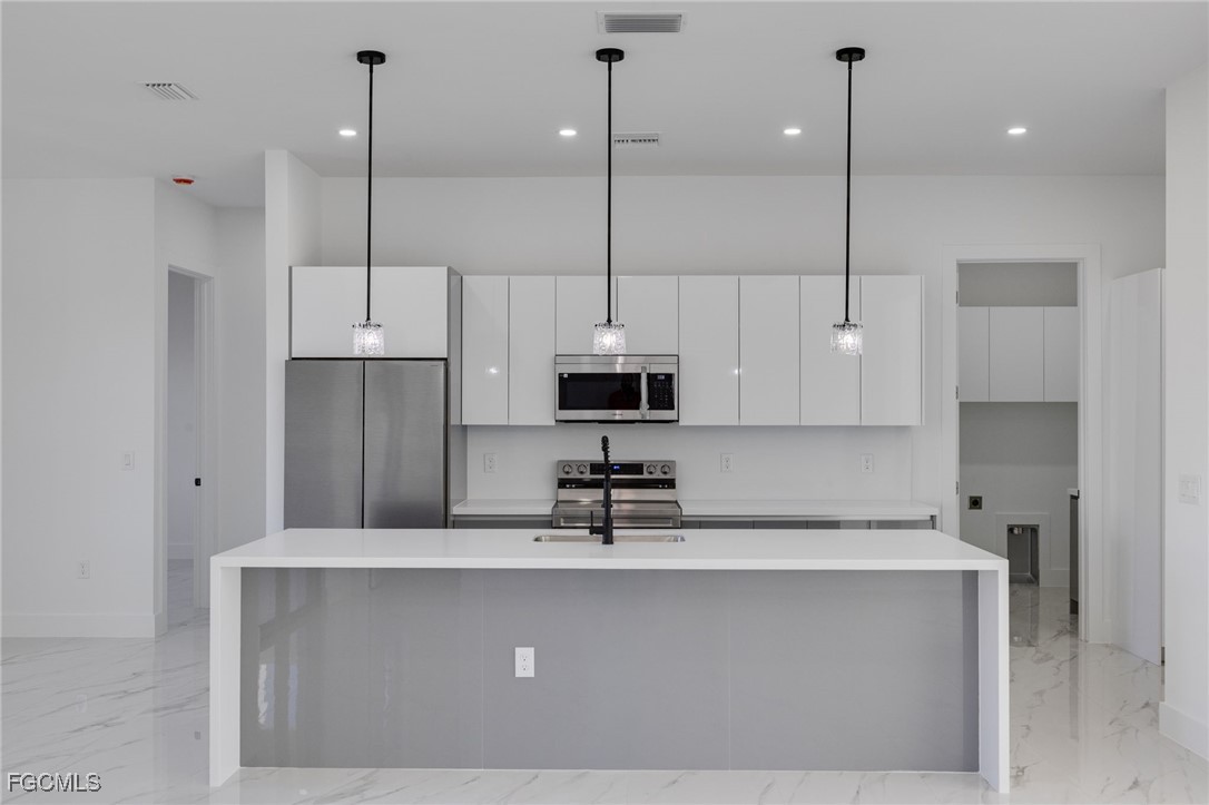 2506 36th Street Southwest Lehigh Acres, FL 33976 - Photo 6 of 25 a kitchen with kitchen island a sink a center island a stove and a window