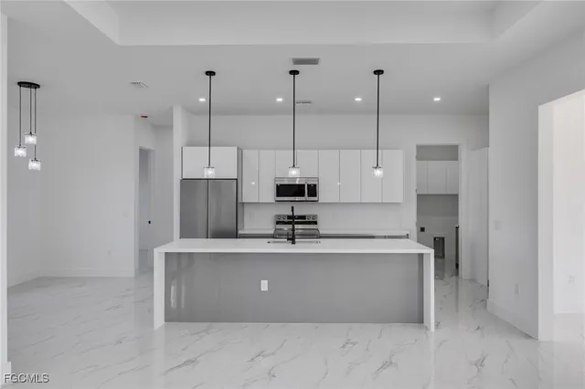 a view of a kitchen with kitchen island a sink stainless steel appliances and cabinets