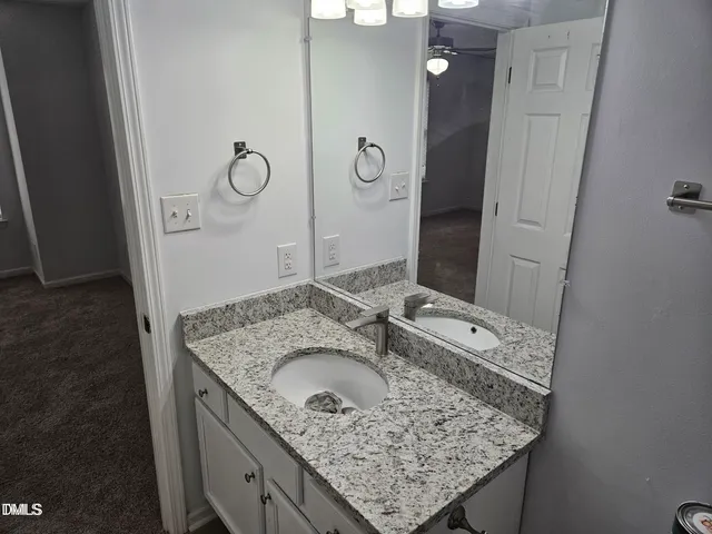 a bathroom with a granite countertop sink a mirror and shower
