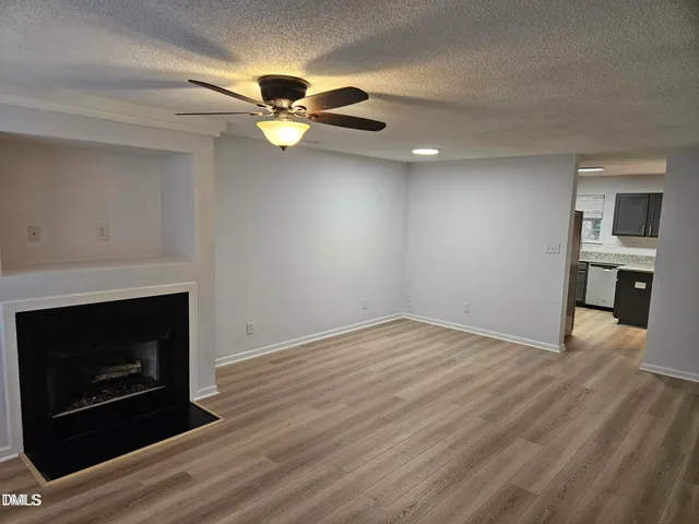 a view of empty room with wooden floor and fireplace