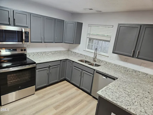 a kitchen with stainless steel appliances granite countertop a sink stove and microwave