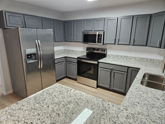 a kitchen with stainless steel appliances kitchen island granite countertop a refrigerator sink and microwave