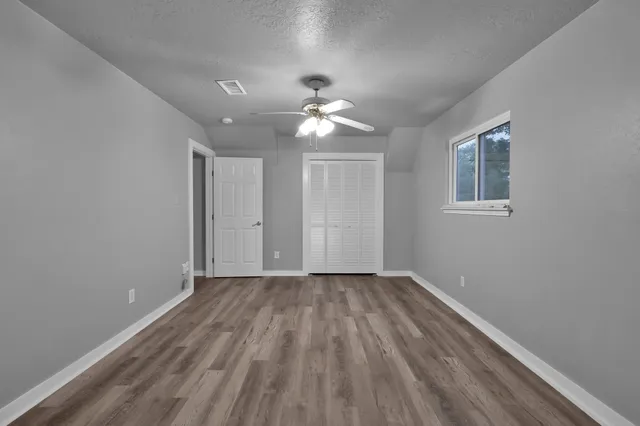 a view of empty room with wooden floor and fan