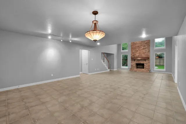an empty room with fireplace cabinet and windows