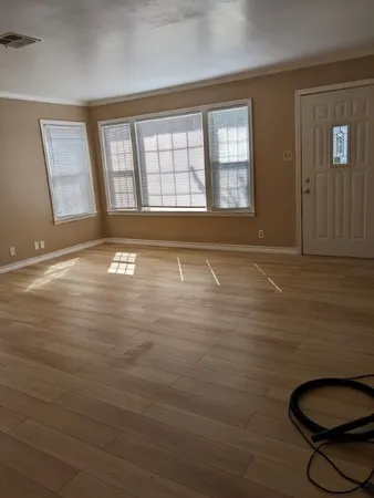 a view of an empty room with a window and wooden floor