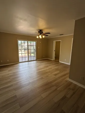 an empty room with wooden floor and fan