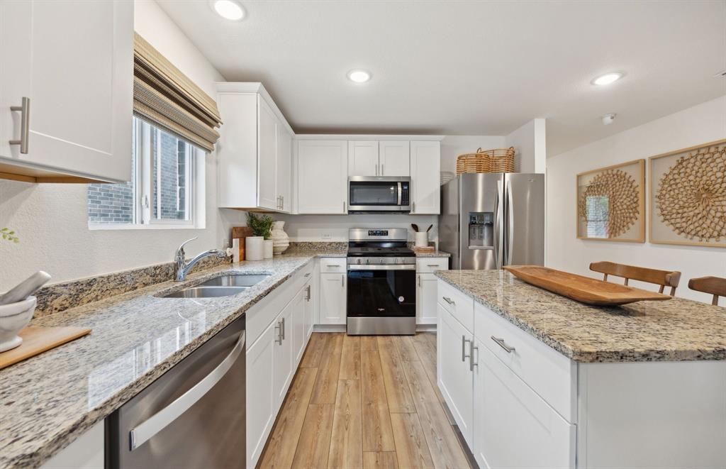 14069 Ladbroke Street Pilot Point, TX 76258 - Photo 2 of 12 a kitchen with granite countertop kitchen island wooden cabinets a counter top space a sink stainless steel appliances and windows