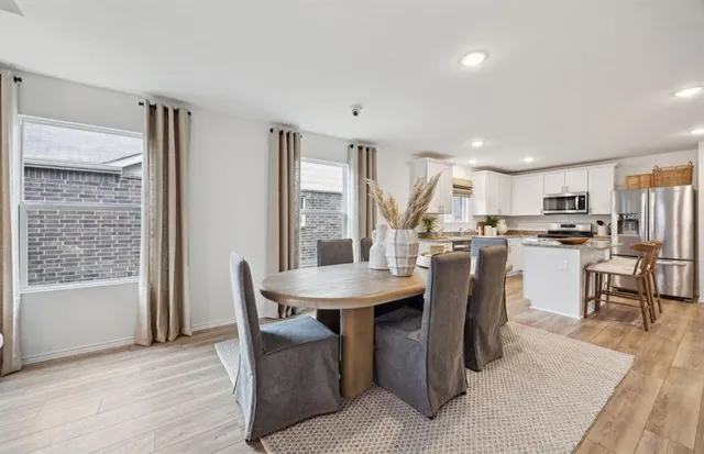 a dining room with stainless steel appliances kitchen island granite countertop a table chairs and a refrigerator