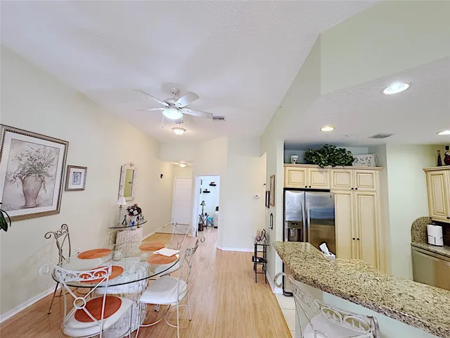 a dining room with stainless steel appliances kitchen island granite countertop a table chairs and a refrigerator