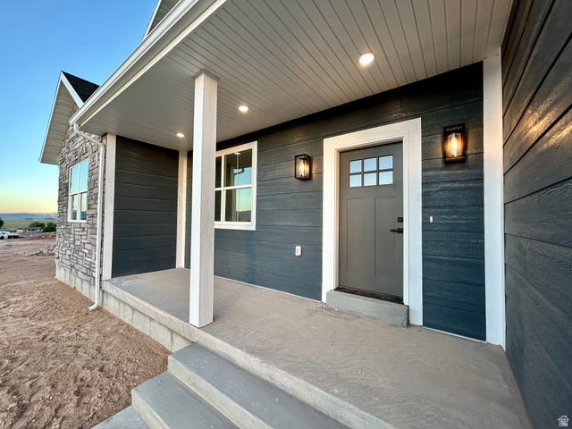 6 South 450th West Gunnison, UT 84634 - Photo 3 of 45 Covered front porch featuring concrete steps, two white support columns, and a gray entry door with decorative lites