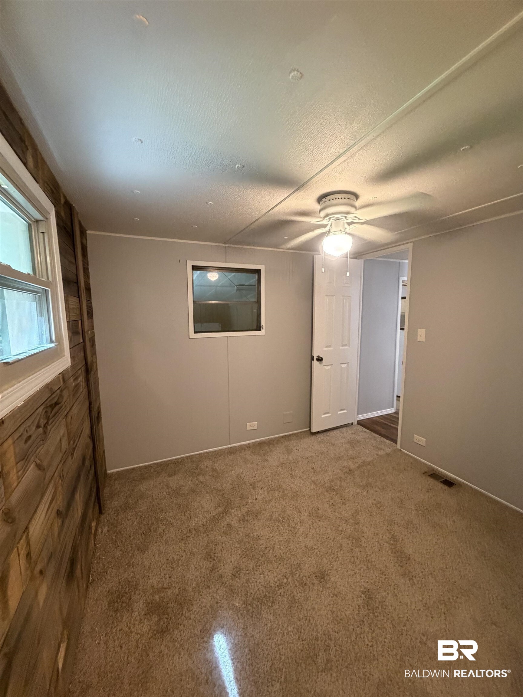 1354 Caney Loop Lillian, AL 36549 - Photo 21 of 45 Carpeted room featuring a ceiling fan with integrated lighting, wood-paneled accent wall, and neutral painted walls