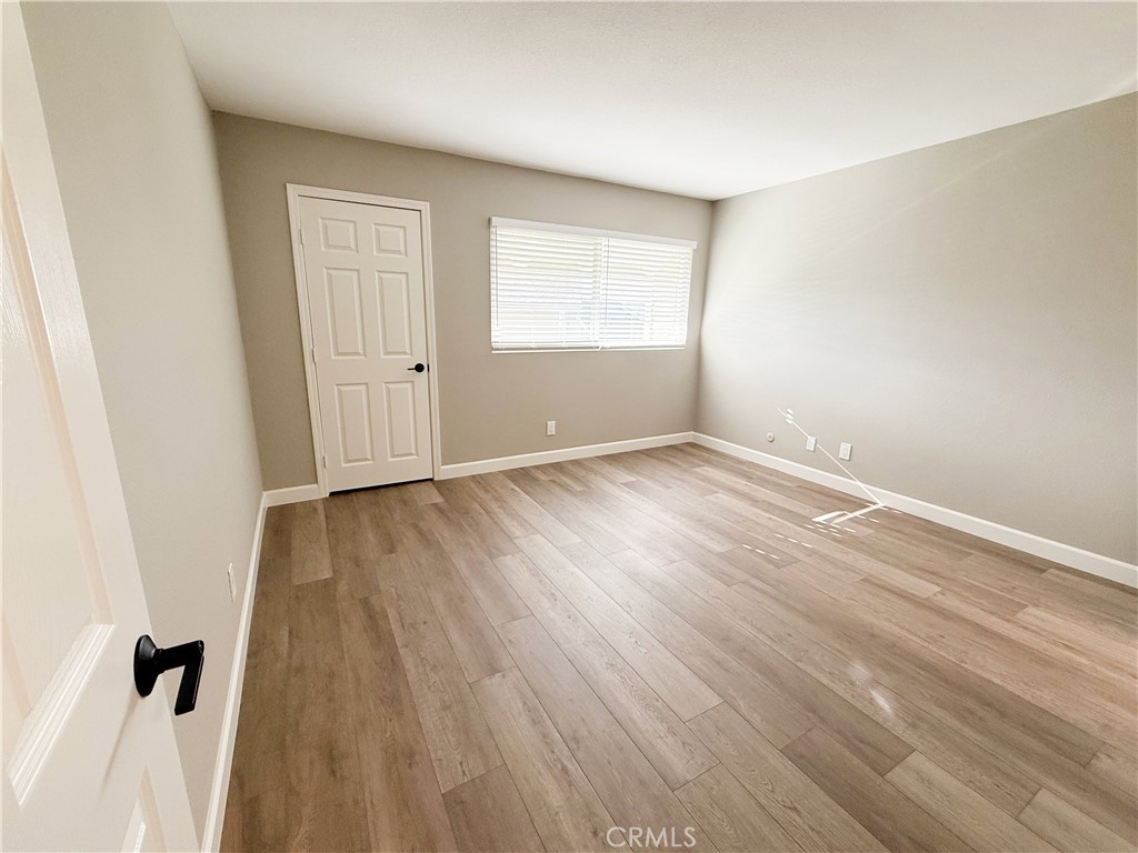 173 Oval Road, Unit 2 Irvine, CA 92604 - Photo 11 of 23 an empty room with wooden floor and windows