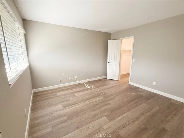 an empty room with wooden floor and windows with curtains