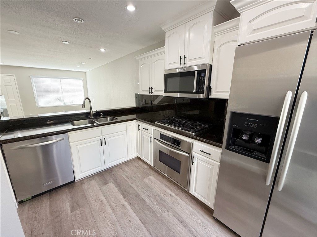 173 Oval Road, Unit 2 Irvine, CA 92604 - Photo 7 of 23 a white kitchen with stainless steel appliances granite countertop a stove a sink and white cabinets