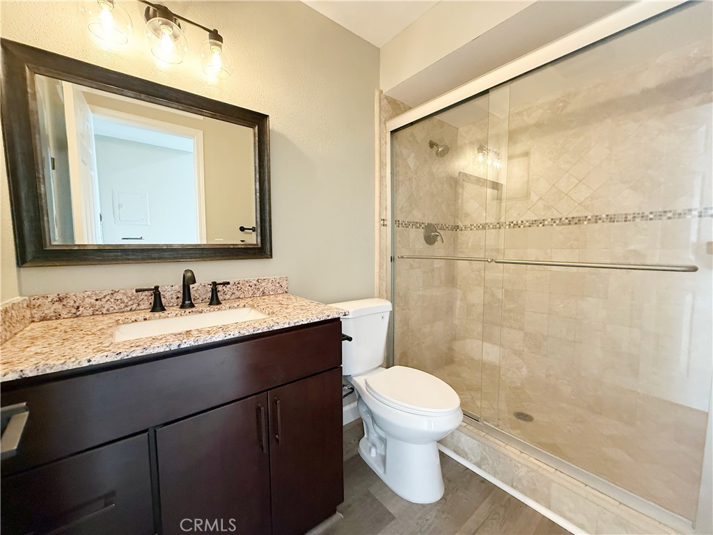 173 Oval Road, Unit 2 Irvine, CA 92604 - Photo 8 of 23 a bathroom with a granite countertop sink toilet a mirror and shower