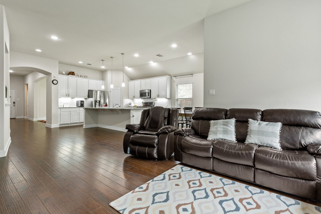 1916 Elaina Loop Leander, TX 78641 - Photo 7 of 23 a large living room with stainless steel appliances kitchen island granite countertop a couch and a view of kitchen