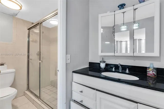 a bathroom with a granite countertop sink a toilet a mirror and shower