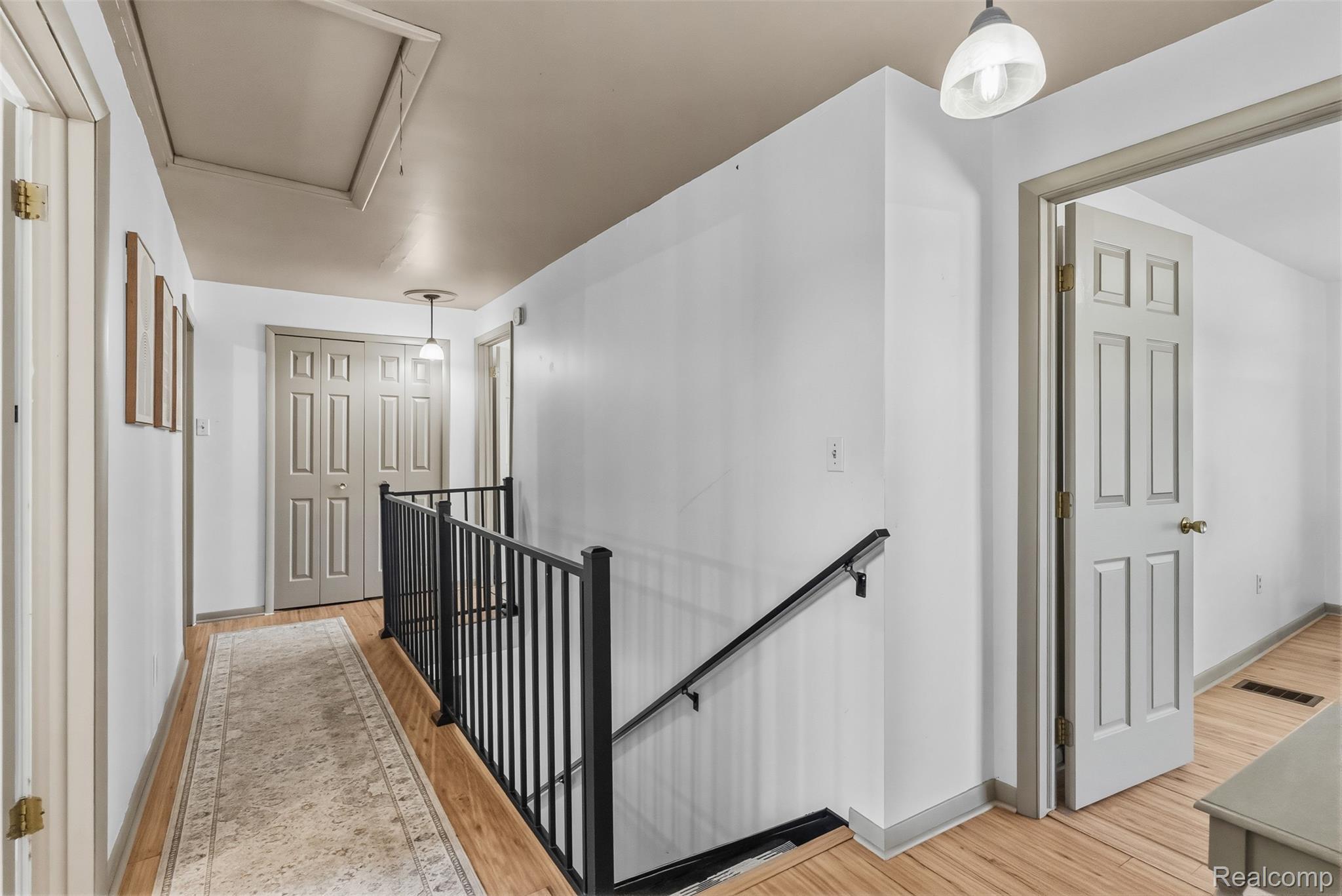 5843 West Dewey Road Owosso, MI 48867 - Photo 25 of 58 Hallway with wood-finish flooring, white walls, and a black metal railing