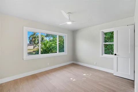 an empty room with wooden floor and windows