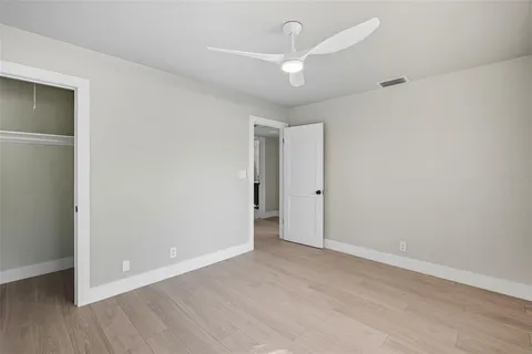 an empty room with wooden floor and a ceiling fan