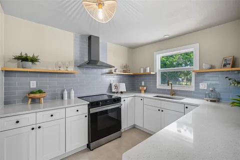 a kitchen with stainless steel appliances granite countertop a sink a stove a window cabinets and a counter top space