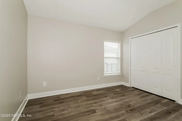 an empty room with wooden floor and window