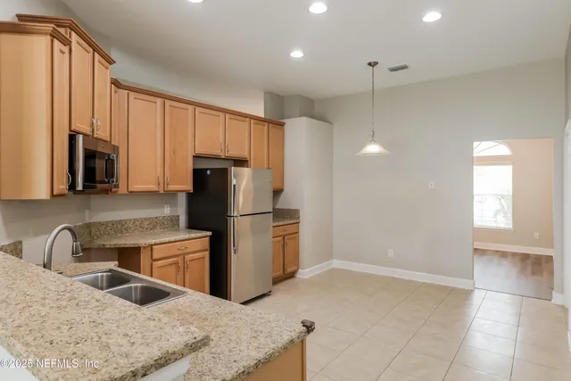 a kitchen with stainless steel appliances granite countertop a refrigerator a stove and a sink with wooden cabinets