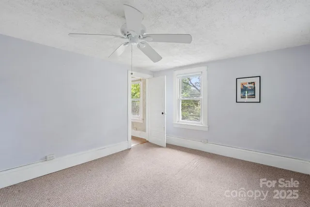 an empty room with windows and fan