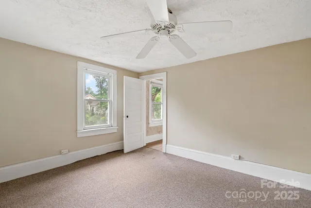 an empty room with windows and fan