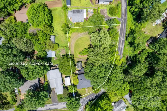 an aerial view of residential house with outdoor space and trees all around