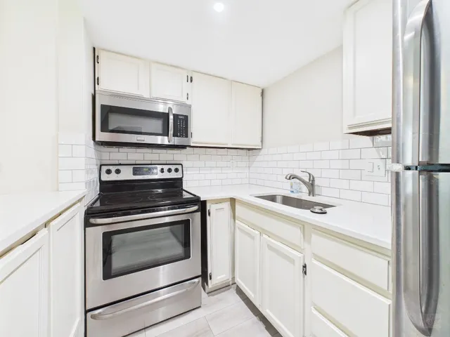 a kitchen with white cabinets stainless steel appliances and sink