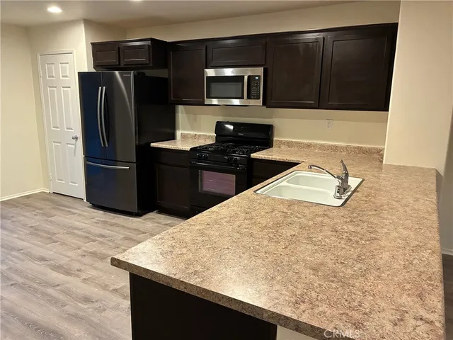 a kitchen with granite countertop a refrigerator stove and microwave